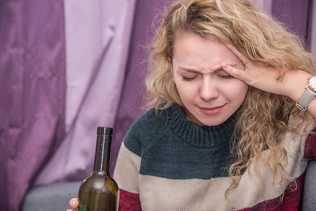 girl with a bottle of wine in his hand, drinking alcohol, headache with a hangover