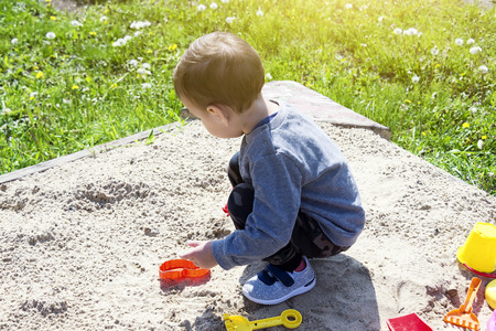 little boy playing in the sand, the child in sunny weather playing in the park on the playground