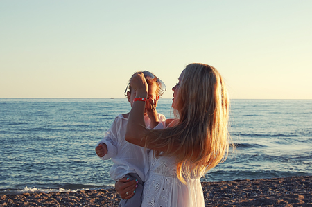 mother with child on the beach in Side, Turkey, against the background of the sea old shipの写真素材