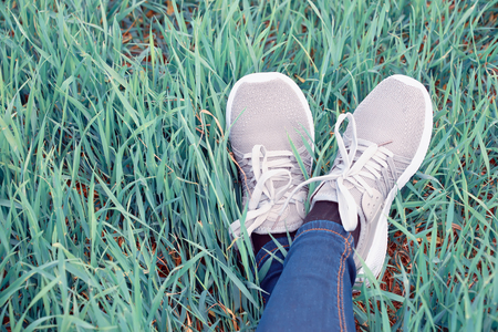 feet in boots on green, juicy grass in warm sunny weatherの写真素材