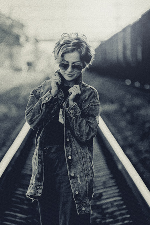 girl on the railway with sunglasses, in a denim jacket art photo, black and white photoの写真素材