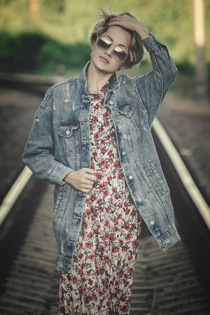 girl on the railway with sunglasses, in a denim jacket art photoの写真素材