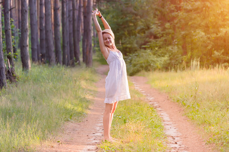 beautiful pregnant girl in the forest raises her hands to the skyの写真素材