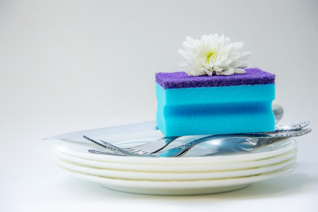 Dish washing sponge on clean dishes close up on white backgroundの写真素材