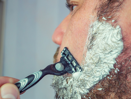 Adult male with a gray beard, shaving with a cream blade, his gray beardの写真素材