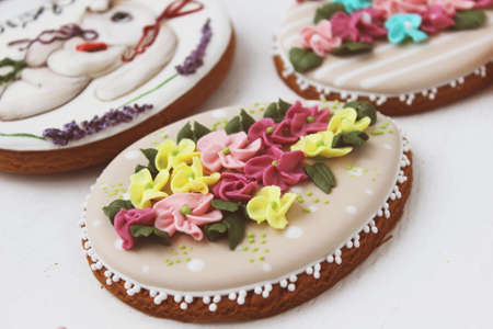 Easter colored gingerbread in the shape of an egg with a rabbit and flowers drawn on them. Close up.の写真素材