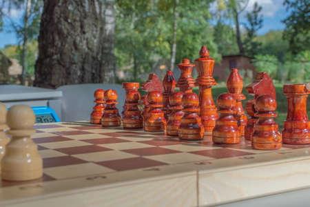 chess pieces white and black on the board at the table outside before the start of the game on a bright evening sunset.の写真素材