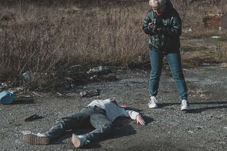 a female forensic expert photographs a dead homeless girl killed during the war on the road at a checkpoint.の写真素材