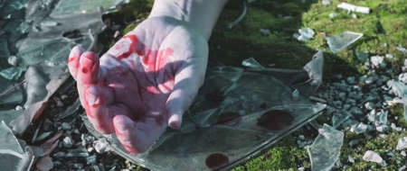 the man's hand is covered in blood on the asphalt on the broken glass on the road after the plane crash.の写真素材