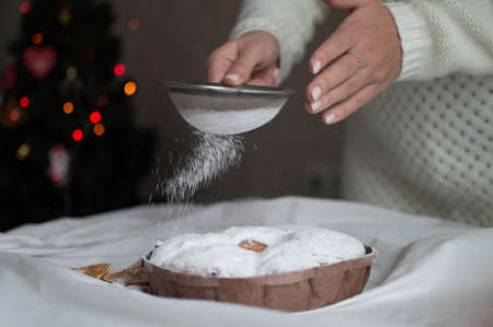 A woman's hands sprinkle powdered sugar on a Christmas cake. New Year and Christmas. Close-up.の写真素材