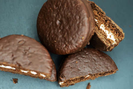 Cookies in chocolate glaze and white cream filling scattered on a dark background. Top view. Close-up.の写真素材