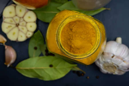 Jar of turmeric, garlic and bay leaf on a dark background. Top view. Close-up.の写真素材