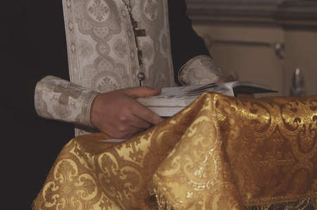 The priest's hands on the Bible when reading prayers. The baptism ceremony. Close-up.の写真素材