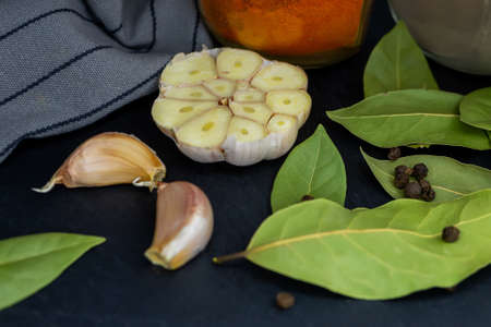 Side view. Jars of spices, bay leaf, garlic and a kitchen towel on a dark background. Close-up.の写真素材