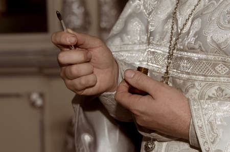 The hands of the priest hold a brush with unctuous oil. The baptism ceremony. Close-up.の写真素材