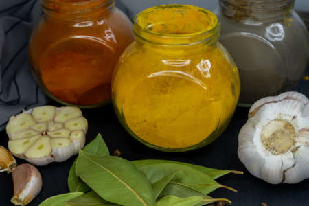 Jars with turmeric, paprika and pepper, garlic and bay leaf on a dark background. Side view. Close-up.の写真素材