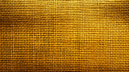A close-up of a rich golden woven fabric, perfect for backgrounds or design elements.の素材