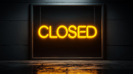 A neo vibrant 'CLOSED' sign glows brightly in warm yellow against a sleek, dark backdrop. The sign is framed within a rectangular black border, suspended by delicate chains, creating a striking contrast. The scene is set in a dimly lit environment with a reflective surface, enhancing the dramatic ambiance and evoking a sense of mystery and exclusivity.の素材