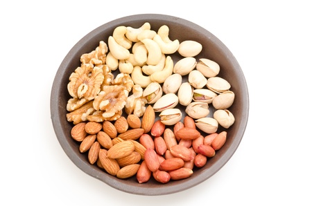 Five kinds of nuts in the earthenware plate isolated on white background
