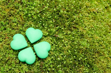 Four green heart shaped objects lined up in form of a clover on the mossの写真素材