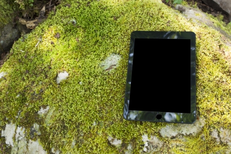 Black tablet computer on the green mossの写真素材