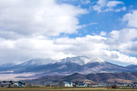 Snow capped mountain range under sky in late autumn of in Hokkaido, Japanの写真素材