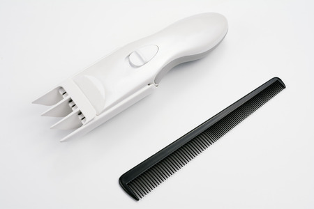 Electric hair clipper and comb on gray background