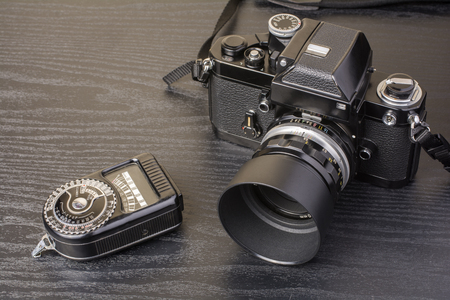 Old camera and exposure meter on dark desk