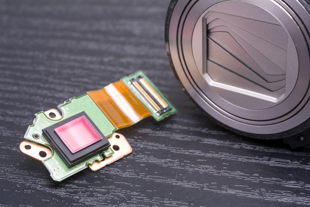 Sensor and lens housing of decomposed digital compact camera on black tableの写真素材