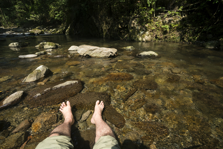 Put man of both feet in gentle stream brook for coolingの写真素材