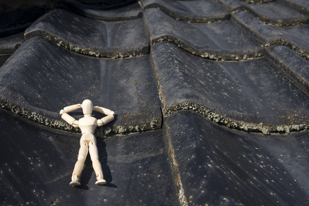 Wooden doll sleeping face up on a asian roof tilesの写真素材