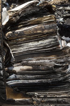 Close up several stacked books burned by fire in vertical compositionの写真素材