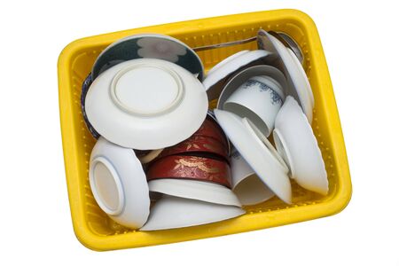 Lot of tableware in a yellow drainer basket on white backgroundの写真素材