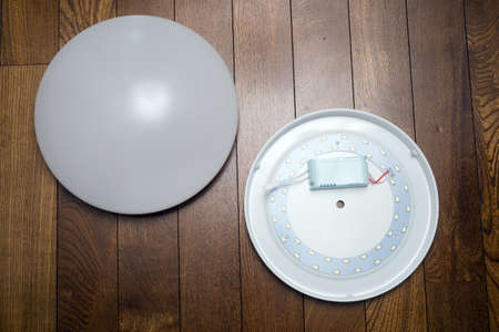 Disassembled Circular LED ceiling light on a wooden floorの写真素材