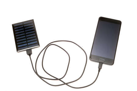 Smartphone charging with solar panel on a white backgroundの写真素材