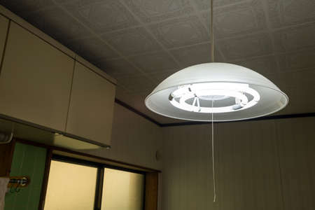 Illuminated fluorescent pendant light hanging in the kitchenの写真素材