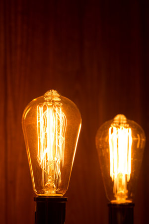 Incandescent lamp filament that emits orange light inside a dark room in vertical compositionの写真素材