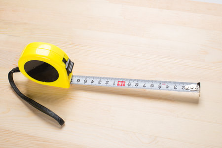 Automatic winding tape measure on a wooden boardの写真素材