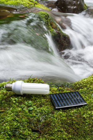 LED light bulb and solar panel on green moss beside brook in vertical compositionの写真素材