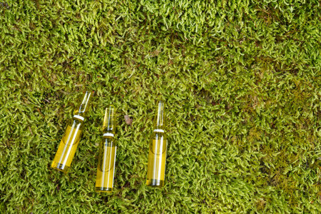 Three thin ampoules on a green mossの写真素材