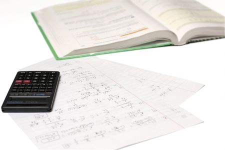 math homework with a calculator and a book on a white backgroundの写真素材