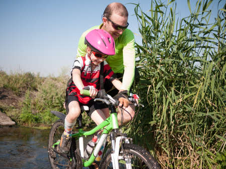 father helping daughter with her bicycleの写真素材