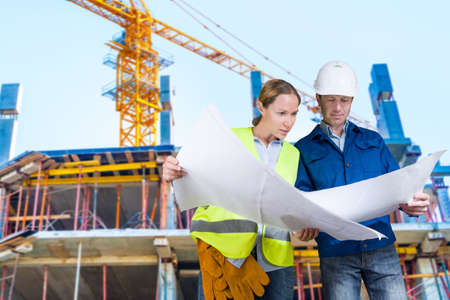 Foreman and engineer with blueprints at construction site