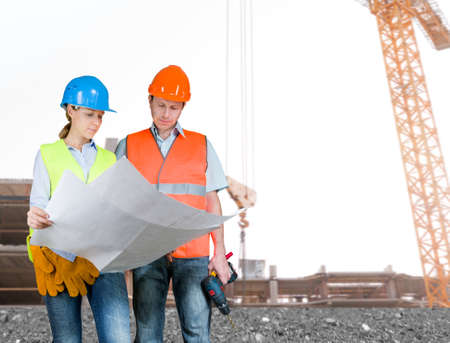 Foreman and engineer with blueprints at construction site