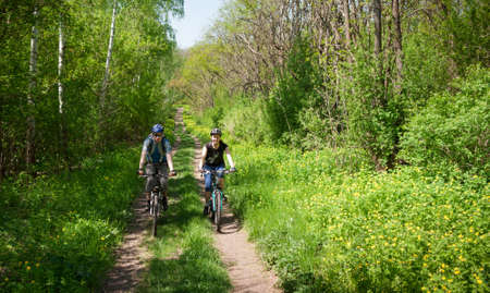 couple cycling in spring forestの写真素材