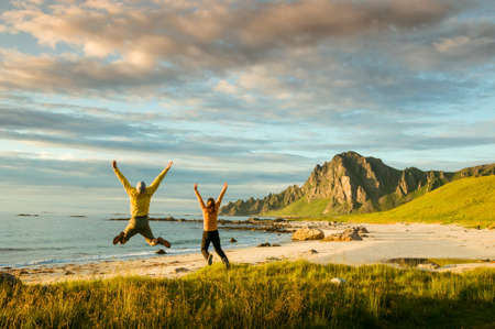 couple jumping on beach in Norwayの写真素材