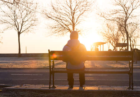 silhouette of woman on bench alone at sunriseの写真素材