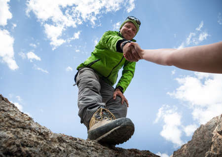 Helping hand couple hikers in mountains