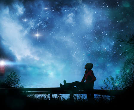 Girl watching the stars in night sky near seaの写真素材