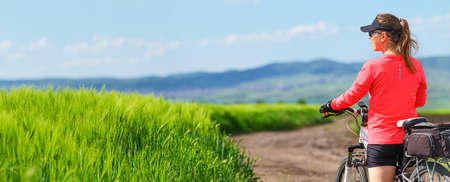 a woman riding bicycle in summer in green fieldの写真素材